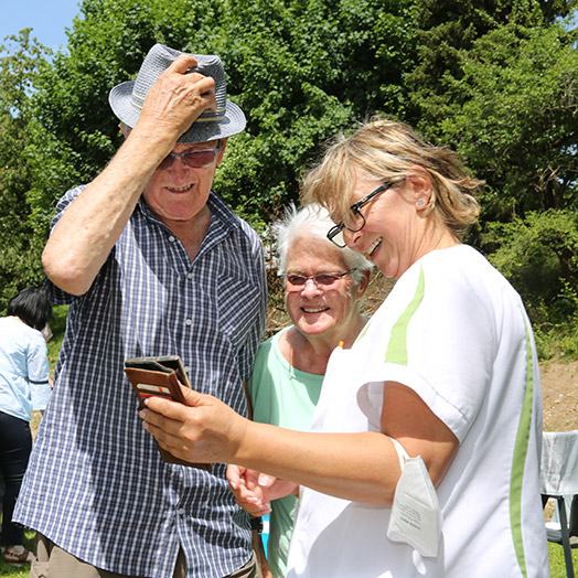 Pflegerin schaut mit Bewohnern ins Handy